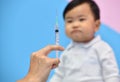 Doctor holding syringe with vaccine for Asian baby Royalty Free Stock Photo