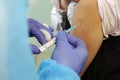 Doctor holding syringe with a vaccine in the shoulder of the patient .