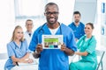 handsome african american doctor holding tablet with colleagues sitting at table