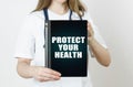 The doctor is holding a tablet with the inscription - PROTECT YOUR HEALTH Royalty Free Stock Photo