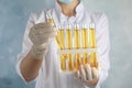 Doctor holding test tubes with urine samples for analysis on light blue background Royalty Free Stock Photo