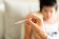 Doctor holding thermometer to measure temperature of her ill kid