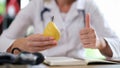 Doctor holding yellow pear and showing thumb-up sign Royalty Free Stock Photo