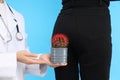 Doctor holds cactus on blue background with woman bottom. Hemorrhoids concept