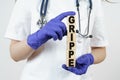 The doctor holds cubes in his hands on which it is written - GRIPPE