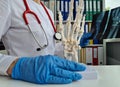 Doctor holds in hands x-ray of the hand and model of skeleton of hands