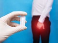 A doctor holds a healing suppository from problems with the rectum and hemorrhoids, the man holds on to the anus of the problem Royalty Free Stock Photo