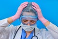 The doctor holds his hands over his head on a blue background, headache. Nurse in medical uniform - stress and fatigue due Royalty Free Stock Photo