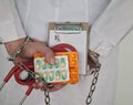 Doctor holds medical prescription pill in handcuffed hand