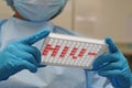 Doctor holds microplate for ELISA with HIV abbrev