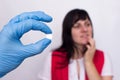 Doctor holds a pill in her hand from oral herpes, the girl holds her lip, pills against herpes, medic