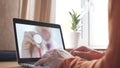 Unknown doctor holds stethoscope bell on the screen of a laptop at home. Modern telemedicine related shot