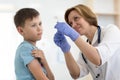 Doctor holds syringe and teenager patient. Little brave boy before injection.