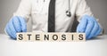 Doctor holds wooden cubes in his hands with text stenosis