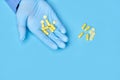 Doctor holds yellow pills in his hands. medical worker in gloves. pharmacology. blue background Royalty Free Stock Photo