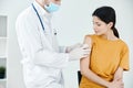 a doctor in a hospital seals a wound on the shoulder of a woman in t-shirt with adhesive tape covid Royalty Free Stock Photo