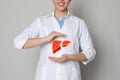 Doctor and illustration of healthy liver on beige background, closeup