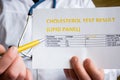 Doctor indicates patient or colleague on cholesterol test result or lipid panel, standing in white medical coat. Concept photo to