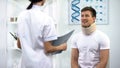 Doctor informing patient in foam cervical collar about good x-ray result, rehab