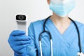 Doctor with infrared thermometer on light background, closeup. Checking temperature during Covid-19 pandemic