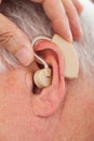 Doctor inserting hearing aid in senior man's ear Royalty Free Stock Photo