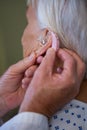 Doctor inserting hearing aid in senior patient ear Royalty Free Stock Photo