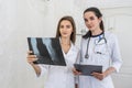 Doctor with intern examining patient`s x-ray. Both wearing medical uniform and standing in hospital Royalty Free Stock Photo