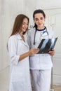 Doctor with intern examining patient`s x-ray. Both wearing medical uniform and standing in hospital Royalty Free Stock Photo