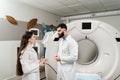 Doctor intern girl is studying in the CT computed tomography scanning room at internship courses. Colleague doctors