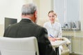 doctor interviews elderly man before being examined in ophthalmologist's office.