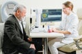 doctor interviews elderly man before being examined in ophthalmologist's office.