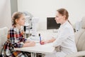 doctor interviews little girl before being examined in ophthalmologist& x27;s office.