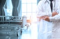 Doctor in lab coat with arms crossed on hospital interior background. Medical concept. Medical information search concept. Disease