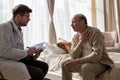 Doctor listening to elderly man complaints visiting him at home