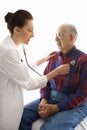 Doctor listening to elderly man's heart.