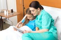 Doctor and little girl using digital tablet and sitting on bed Royalty Free Stock Photo