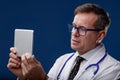 Doctor looking at a digital tablet with thoughtful expression