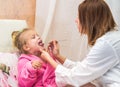 The doctor looks at the patient's throat girl