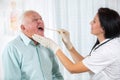 Doctor looks in the throat an older man