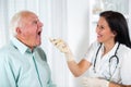 Doctor looks in the throat an older man