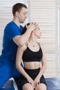 The doctor makes a diagnosis of the head and cervical spine of a young girl. Massage and manual therapy