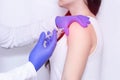 Doctor makes an injection of blockade of chondroprotector and anti-inflammatory drug in the girl`s sore shoulder, white backgroun