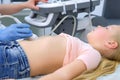 Doctor is making abdominal ultrasound for child girl using scanner, side view.