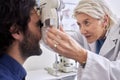 Doctor with a man in vision test or eye exam for eyesight by a focused senior optometrist or ophthalmologist. Optician Royalty Free Stock Photo