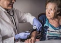 Doctor measures the arterial tension to oldster at home Royalty Free Stock Photo