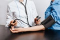 Doctor measures blood pressure with a tonometer to a woman patient at a medical appointment in a clinic Royalty Free Stock Photo