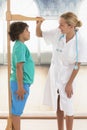 Doctor measures growth smiling boy in medical office, profile vi Royalty Free Stock Photo