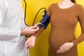 Doctor measures the pressure of a pregnant woman on colourful background Royalty Free Stock Photo