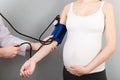 Doctor measures the pressure of a pregnant woman on colourful background Royalty Free Stock Photo