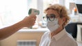 The doctor measures the temperature of an elderly woman with an electronic thermometer